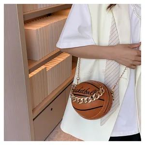 Detail of a brown basketball-shaped crossbody bag with dual gold chain straps and texture