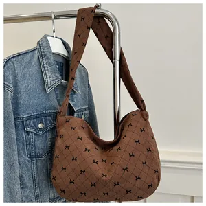 Detailansicht der braunen Cord-Hobo-Tasche mit schwarzem Schleifendruck und Trageriemen