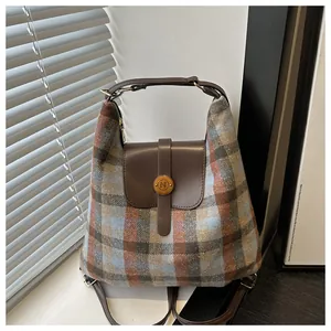 Detail of plaid tote bag with brown leather flap and golden N-engraved buckle