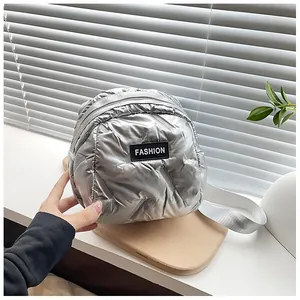 Detailed shot of metallic silver puffer backpack featuring quilted fabric and fashion logo