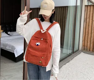 Detailed texture of orange corduroy backpack with cute doll charm and embroidery
