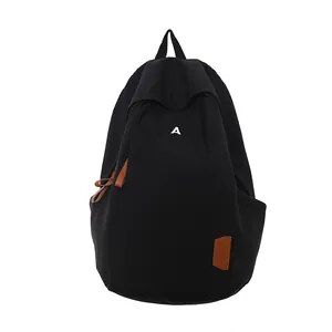Minimalist black student backpack with white letter A logo and brown leather accents