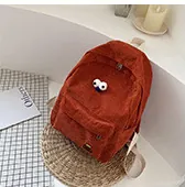 Detail of caramel corduroy backpack with cute cartoon eyes on a woven mat