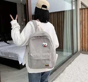 Detail of light gray corduroy backpack featuring cartoon 3D eyes and embroidery