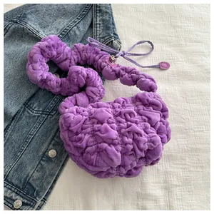 Macro shot of purple pleated plush bag with metallic buckle on denim jacket background