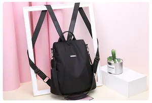 Detail of black anti-theft nylon backpack with metallic nameplate and detachable strap