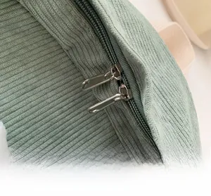 Close-up of smooth double metal zippers and corduroy texture on green backpack