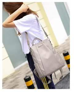 Detail view of a light gray nylon backpack with adjustable metal buckles and side pockets