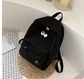 Detail view of mini black corduroy backpack with funny big eye and orange patches