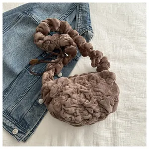 Close-up of brown plush cloud bag with soft pleated handle on denim background