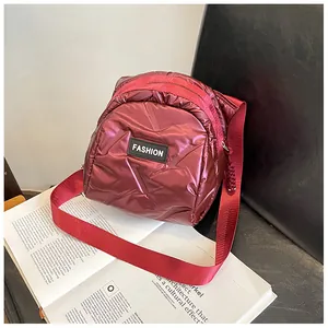 Detail of burgundy quilted puffer bag with Fashion patch and wide nylon shoulder strap