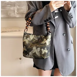 Vue détaillée de la poignée en perles de bois sombres sur un sac brodé de papillons