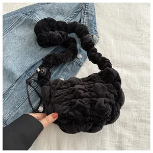 Detail of black plush pleated cloud bag featuring a ruched shoulder strap texture