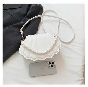 Detalle de bolso de fiesta blanco con forma de concha y cadena de perlas elegantes
