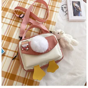 Dettaglio borsa a tracolla rosa in nylon con pompon bianco e ciondoli a forma di papera