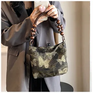 Détail de la poignée perlée et broderie papillon dorée sur le sac à main en jacquard