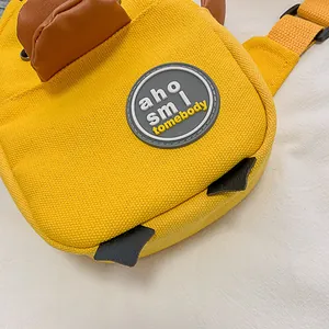 Bolso bandolera de lona amarilla con parche redondo decorativo y detalles de cuero
