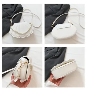 Detalle del bolso blanco en forma de concha con asa de perlas y herrajes dorados