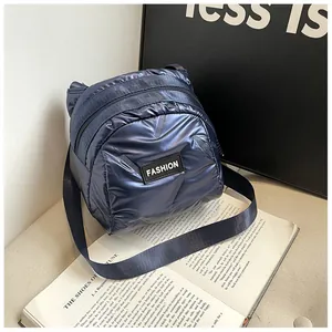 Deep blue quilted puffer crossbody bag with glossy metallic finish and fashion label