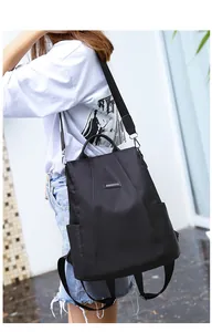Detail of black nylon anti-theft backpack with metal logo and adjustable shoulder straps