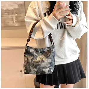 Détails de la poignée en perles de bois et broderie papillon sur le sac à main