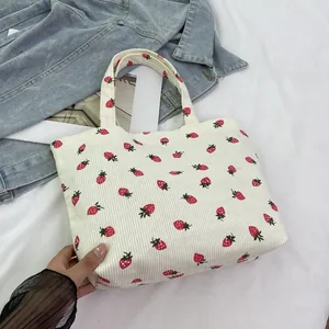 White corduroy tote bag with red strawberry prints and double handles for daily use