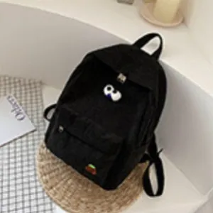 Minimalist black corduroy backpack for women featuring an orange badge and heart detail