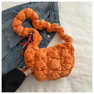 Detail of bright orange pleated puff shoulder bag with soft quilted bubble texture fabric