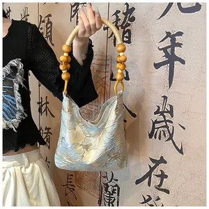 Détail de la poignée en perles de bois et broderie florale sur un sac à main en soie