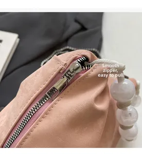 Detalle de cremallera suave y asa de cuerda con cuentas blancas en un bolso rosa fruncido