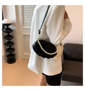 Bolso bandolera negro tipo concha en modelo con cadena de perlas y acabado de cuero plisado