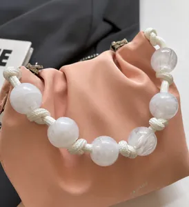Detalle del bolso nube rosa plisado con asa de cuentas de acrílico blanco y textura suave