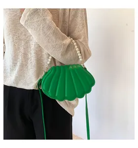 Detalle del bolso de noche de concha verde con asa de perlas grandes y bandolera
