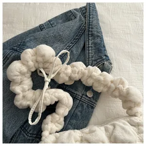 Detail shot of the white plush cloud bag showing soft faux fur texture and tie-knot strap