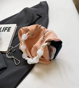 Vista de detalle del bolso rosa con asa de perlas y espacioso interior para un teléfono