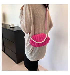 Detalle del bolso de concha rosa púrpura con asa de perlas grandes y cadena decorativa