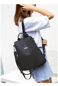 Detail of black waterproof nylon backpack with versatile straps and metal logo plate