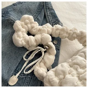 Detail of white plush shoulder bag featuring soft pleated texture and silver metal clasp