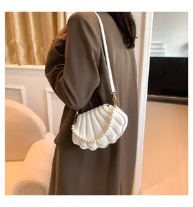 Detalle del bolso de noche blanco tipo concha con asa de perlas y textura de piel plisada