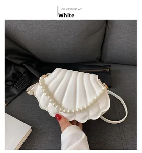 Detalle del bolso de fiesta blanco con forma de concha, asa de perlas y pliegues