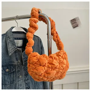 Detail of bright orange pleated plush handbag hanging next to a blue denim jacket