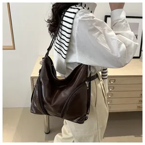 Detail of soft dark brown leather tote bag with stylish side zippers and adjustable strap