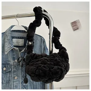 Detail view of the black ruched plush cloud bag hanging against a denim jacket