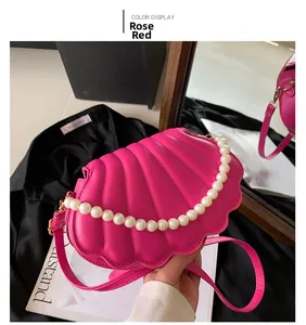 Detalle del bolso bandolera fucsia con diseño de concha, textura acolchada y perlas