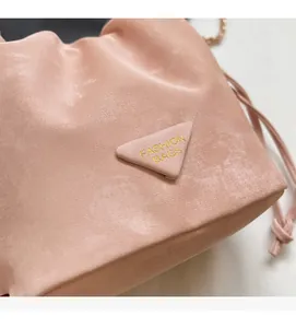 Détail d'un sac seau rose à cordon montrant la texture suédée et le logo triangulaire