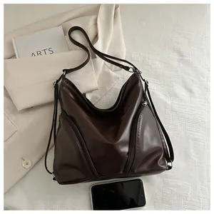 Deep brown faux leather hobo bag next to a smartphone showing its large storage capacity