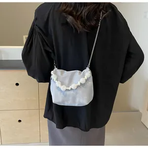 Detalle del bolso plisado gris claro con cuentas blancas y correa de cadena plateada