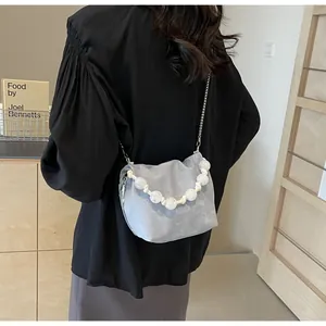 Detalle de bolso cubo de ante gris claro con asa de cuentas blancas y cadena plateada