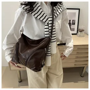 Detailed view of dark brown matte leather hobo bag with zip pockets and adjustable strap
