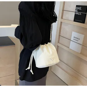 Détail du sac seau en toile crème avec fermeture à cordon et bandoulière chaîne